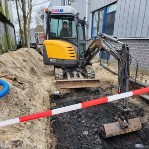 Een medewerker van Otte Infra is bezig met het saneren van verontreinigde grond met een Volvo kraantje op een kavel in Alphen aan de Rijn.